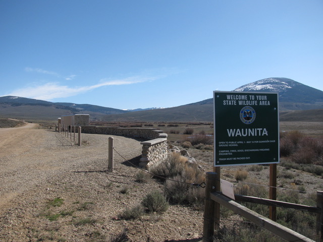 The viewing site, a curved gravel pullout with a rock wall and a small enclosure. A signs says "welcome to your state wildlife area, Waunita."